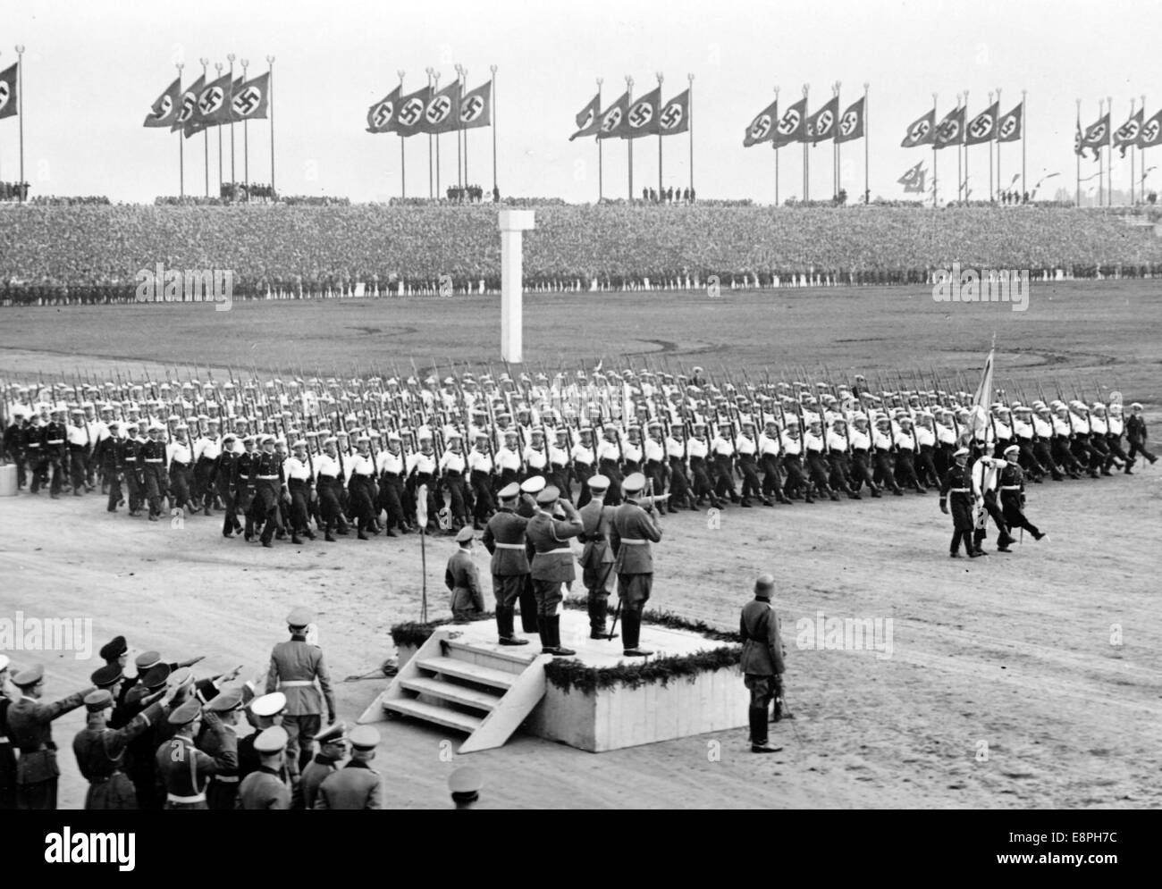 Nuremberg Rally 1937 in Nuremberg, Germany - Nazi party rally grounds - Demonstration by the German Wehrmacht (armed forces) on Zeppelin Field, here the Navy's non-commissioned officer training course marches past Adolf Hitler. To the right of Hitler: Field Marshal Werner von Blomberg. Behind them: The commanders of the three Wehrmacht branches Grand Admiral Erich Raeder, Colonel General Freiherr Werner von Fritsch and Colonel General Hermann Goering. Flaws in quality due to the historic picture copy) Fotoarchiv für Zeitgeschichtee - NO WIRE SERVICE - Stock Photo