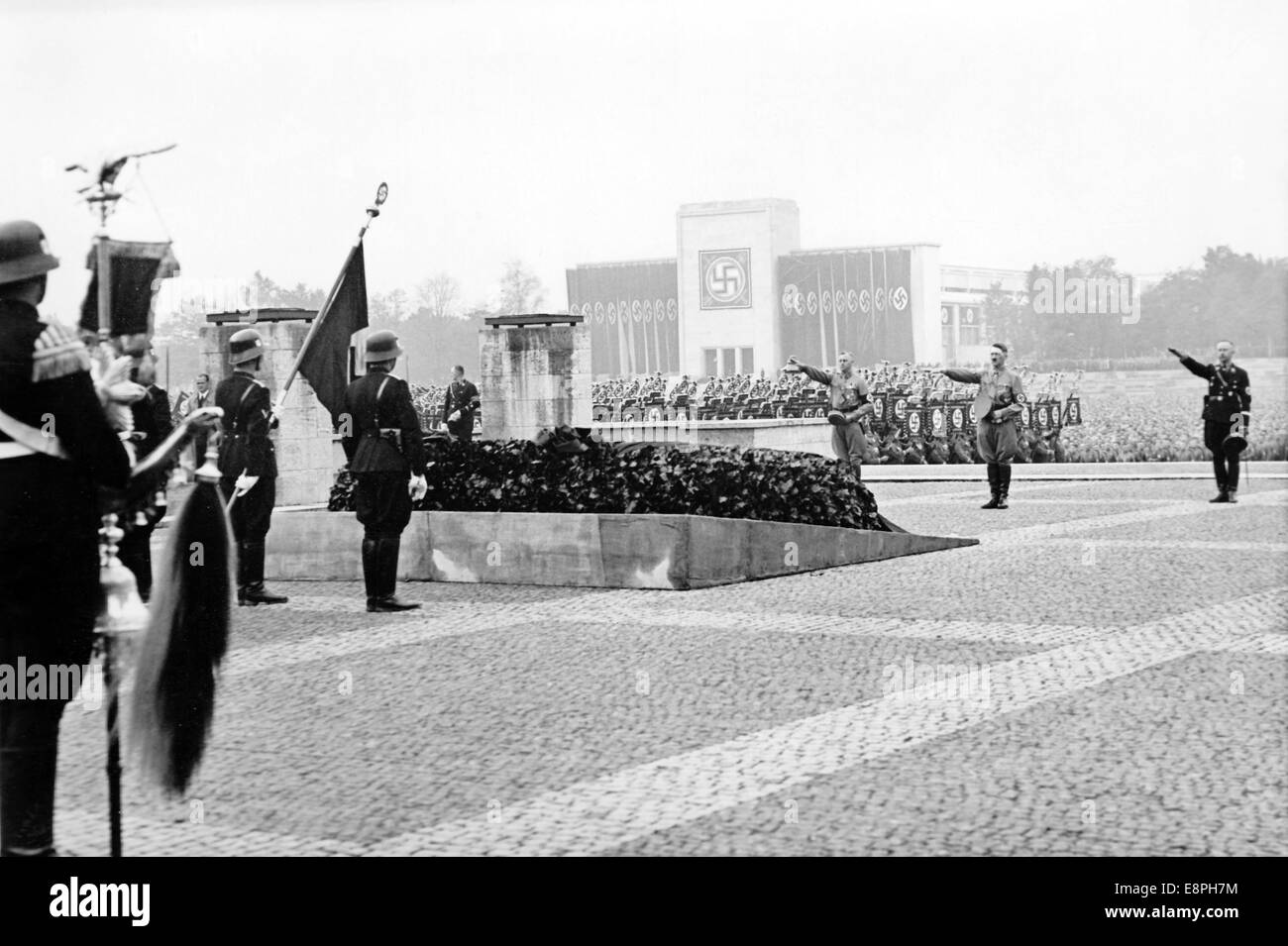 Nuremberg Rally 1937 in Nuremberg, Germany - Nazi party rally grounds - Adolf Hitler, commander of the Sturmabteilung (SA) Viktor Lutze (L) and Reichsfuehrer of the Schutzstaffel (SS) Heinrich Himmler (R) attend the commemoration of the 'heroes', who fell in the failed Beer Hall Putsch in 1923 in front of the 'Hall of Honour' during the roll call of the Sturmabteilung (SA), Schutzstaffel (SS), National Socialist Motor Corps (NSKK) and National Socialist Flyers Corps (NSFK). Luitpold Hall, which had been renovated from 1933 till 1935, is seen in the background. (Flaws in quality due to the hist Stock Photo
