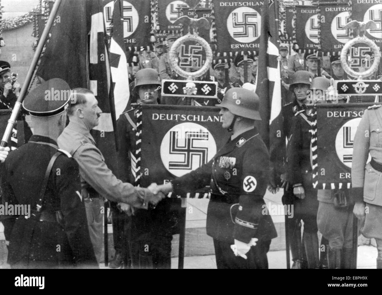 Nuremberg Rally 1937 in Nuremberg, Germany - Adolf Hitler consecrates new standards with the 'Blood Flag' during the roll call of Sturmabteilung (SA), Schutzstaffel (SS) and National Socialist Motor Corps (NSKK), here handshake after the consecration. New standards were consecrated by touching them with the 'Blood Flag' which supposedly was carried in the failed Beer Hall Putsch in Munich. (Flaws in quality due to the historic picture copy) Fotoarchiv für Zeitgeschichtee - NO WIRE SERVICE - Stock Photo