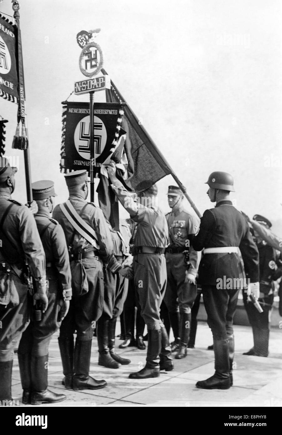 Nuremberg Rally 1938 in Nuremberg, Germany - The new standards are consecrated by Adolf Hitler with the 'Blood Flag', behind Hitler the standard bearer Jakob Grimminger. During the consecration of the flags new standards of Sturmabteilung (SA) und Schutzstaffel (SS) were touched to the 'Blood Flag', which supposedly was carried during the failed Beer Hall Putsch, and thereby consecrated. (Flaws in quality due to the historic picture copy) Fotoarchiv für Zeitgeschichtee - NO WIRE SERVICE - Stock Photo