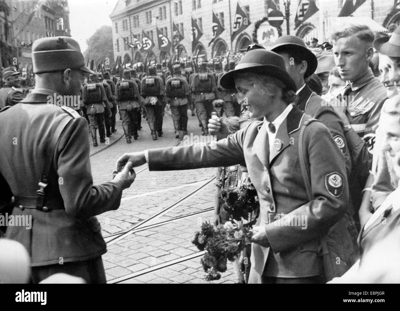 Nuremberg Rally 1937 in Nuremberg, Germany - A female member of the Reich Labour Service (RAD) offers refreshments to male members of the RAD as they march through the streets of the city with spades and knapsacks. (Flaws in quality due to the historic picture copy) Fotoarchiv für Zeitgeschichtee - NO WIRE SERVICE - Stock Photo