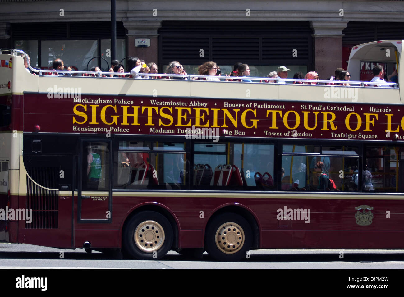 An open top double decker tour bus being driven in London with passengers on the upper deck Stock Photo