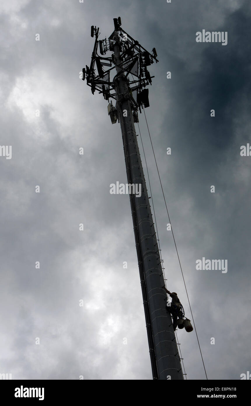 A tower construction worker makes his way down from the top of a Communications Tower to avoid an approaching thunderstorm. Stock Photo