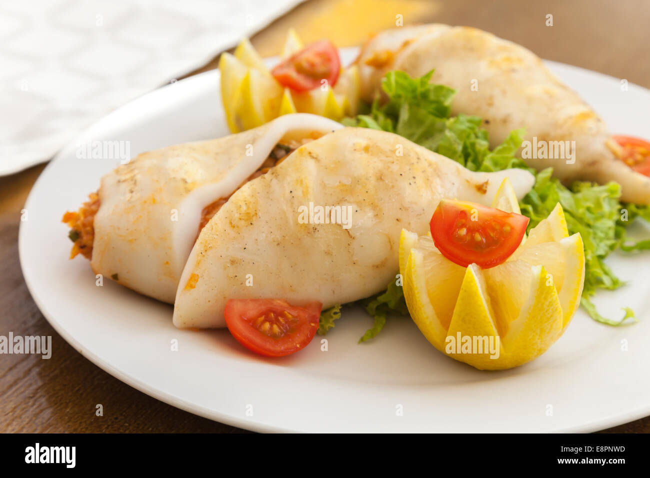 Squids stuffed with seafood on white plate in restaurant Stock Photo