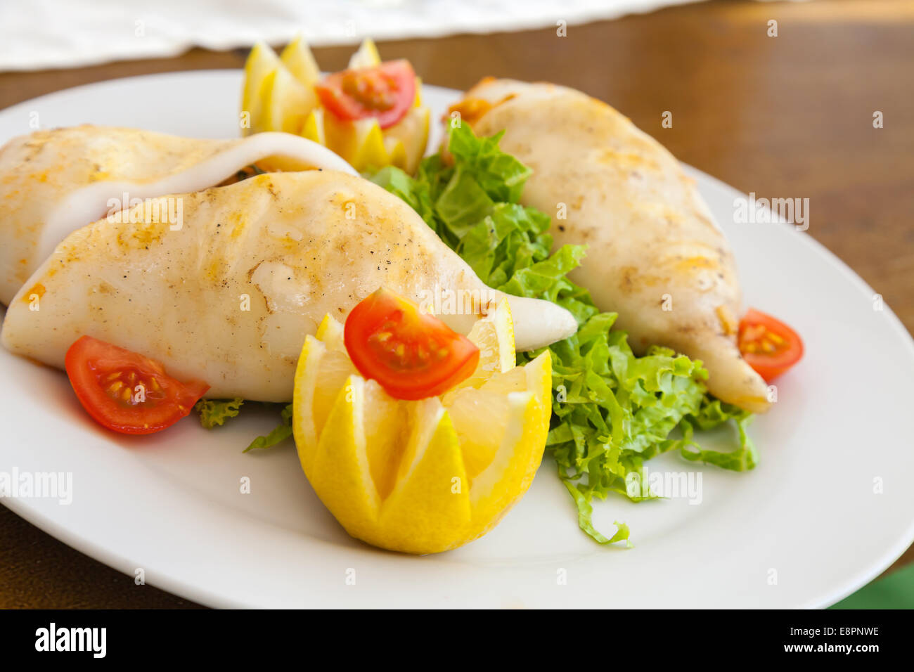 Squid stuffed with seafood on white plate in the restaurant Stock Photo