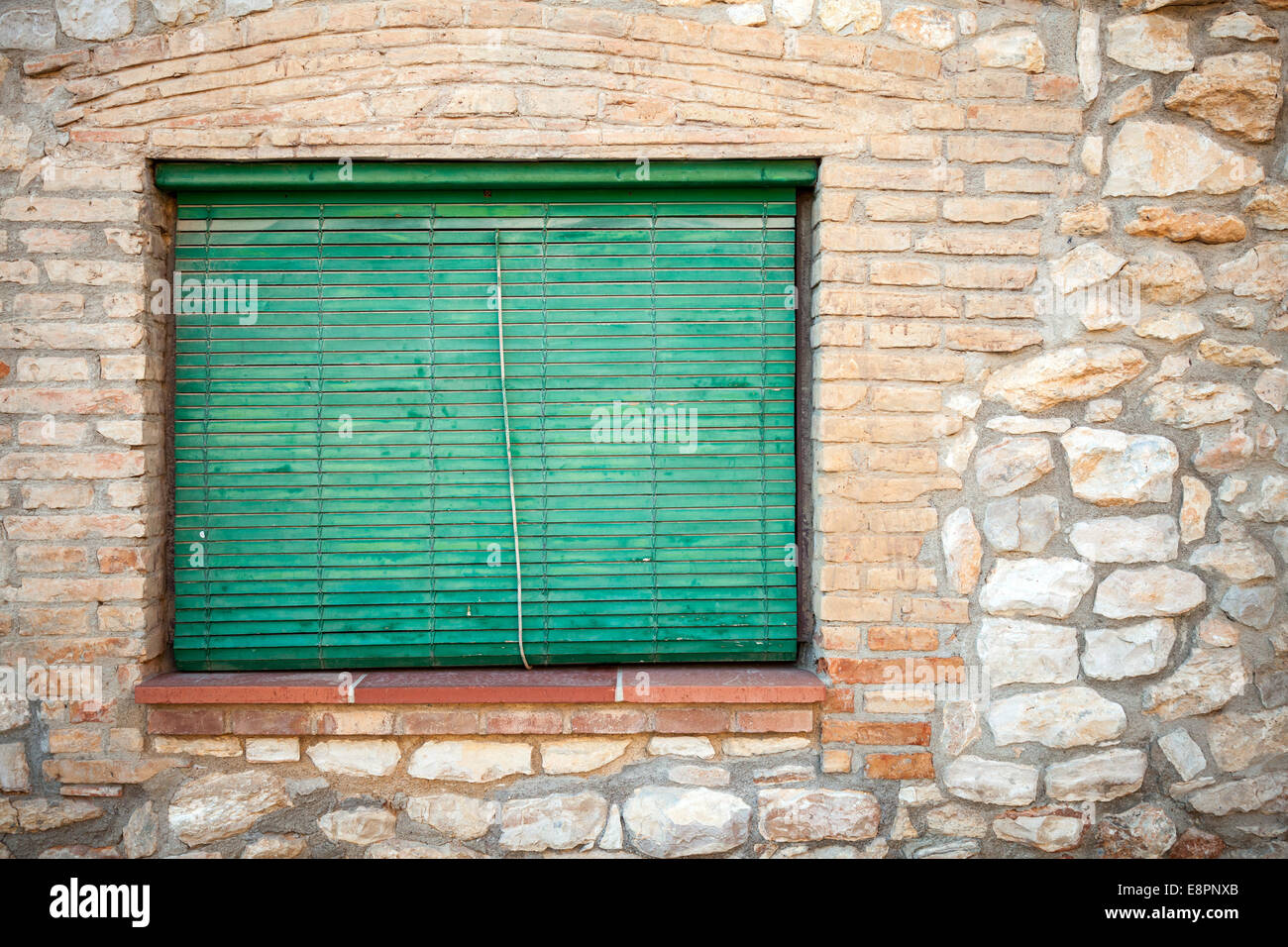 Old stone facade with green wooden shutters in the window. Background texture Stock Photo