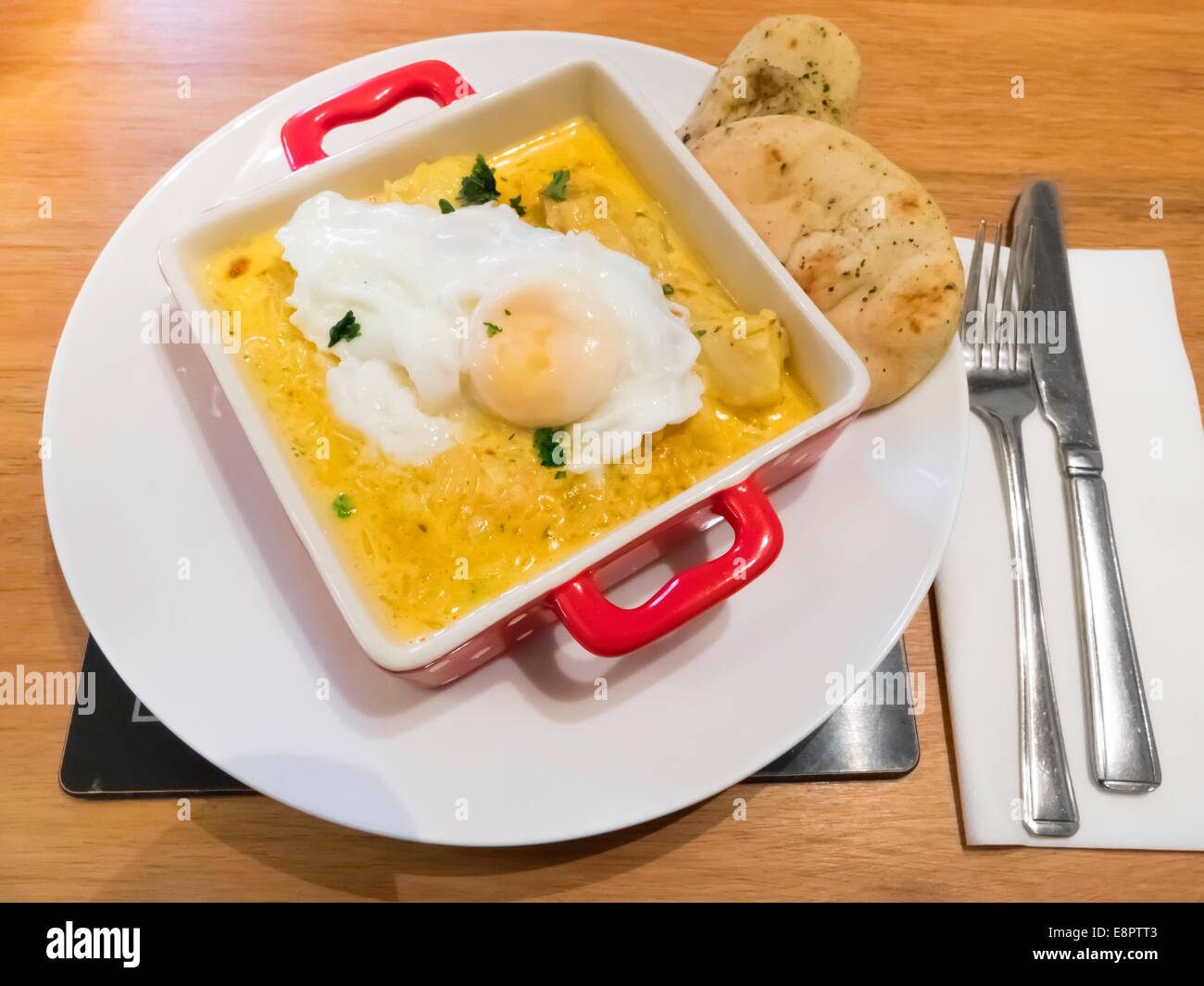 A light lunch of kedgeree a dish made from curried smoked haddock and rice with a poached egg and Indian Naan bread Stock Photo