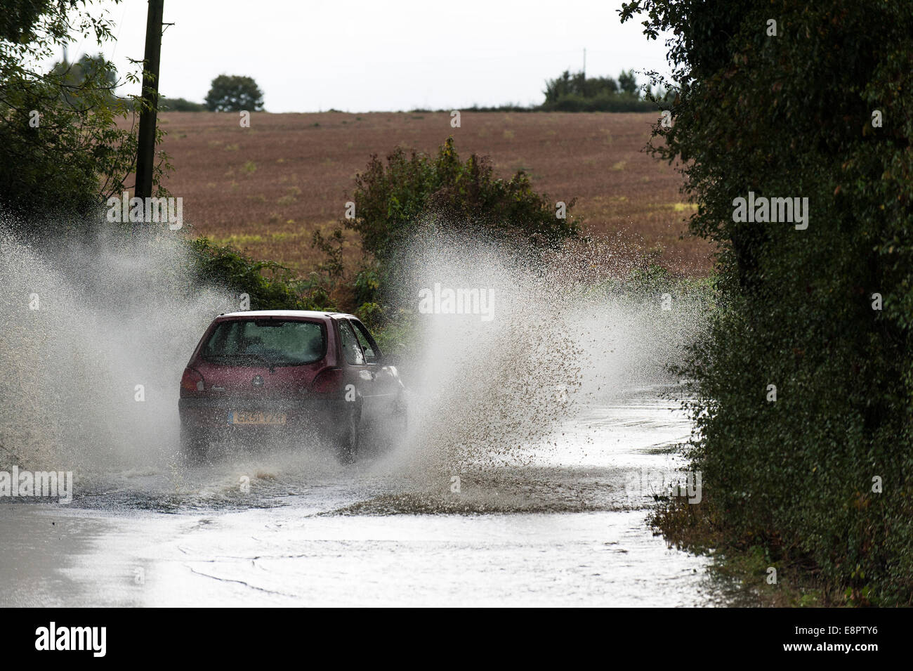 Essex, UK. 13th October, 2014.  Vehicles driving through a flooded road near Buttsbury in Essex after overnight torrential rain. Credit:  Gordon Scammell/Alamy Live News Stock Photo