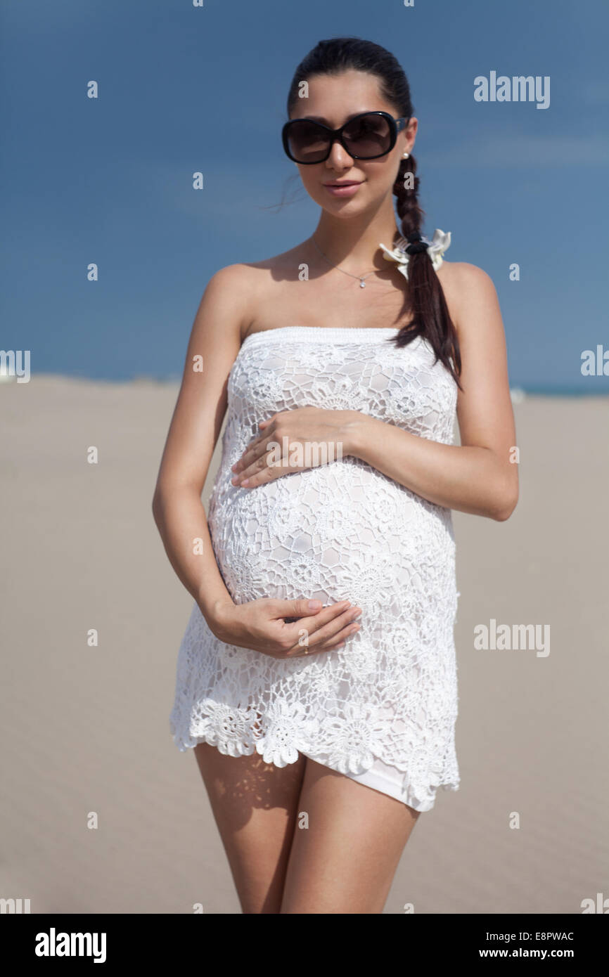 Pregnant woman in white bikini posing on the beach Stock Photo