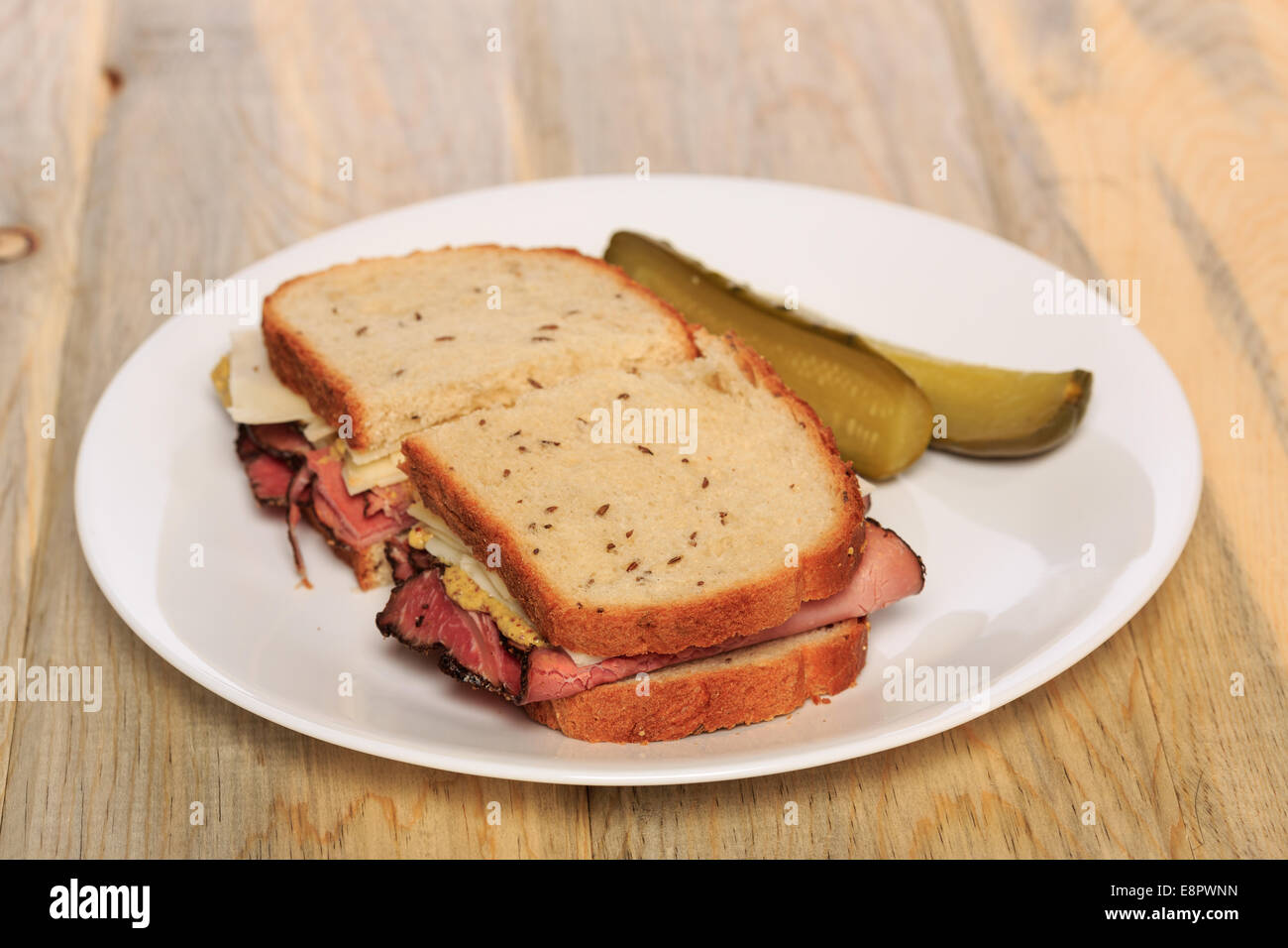 Pastrami sandwich on Jewish Rye bread with swiss cheese, mustard, and kosher dill pickles Stock Photo