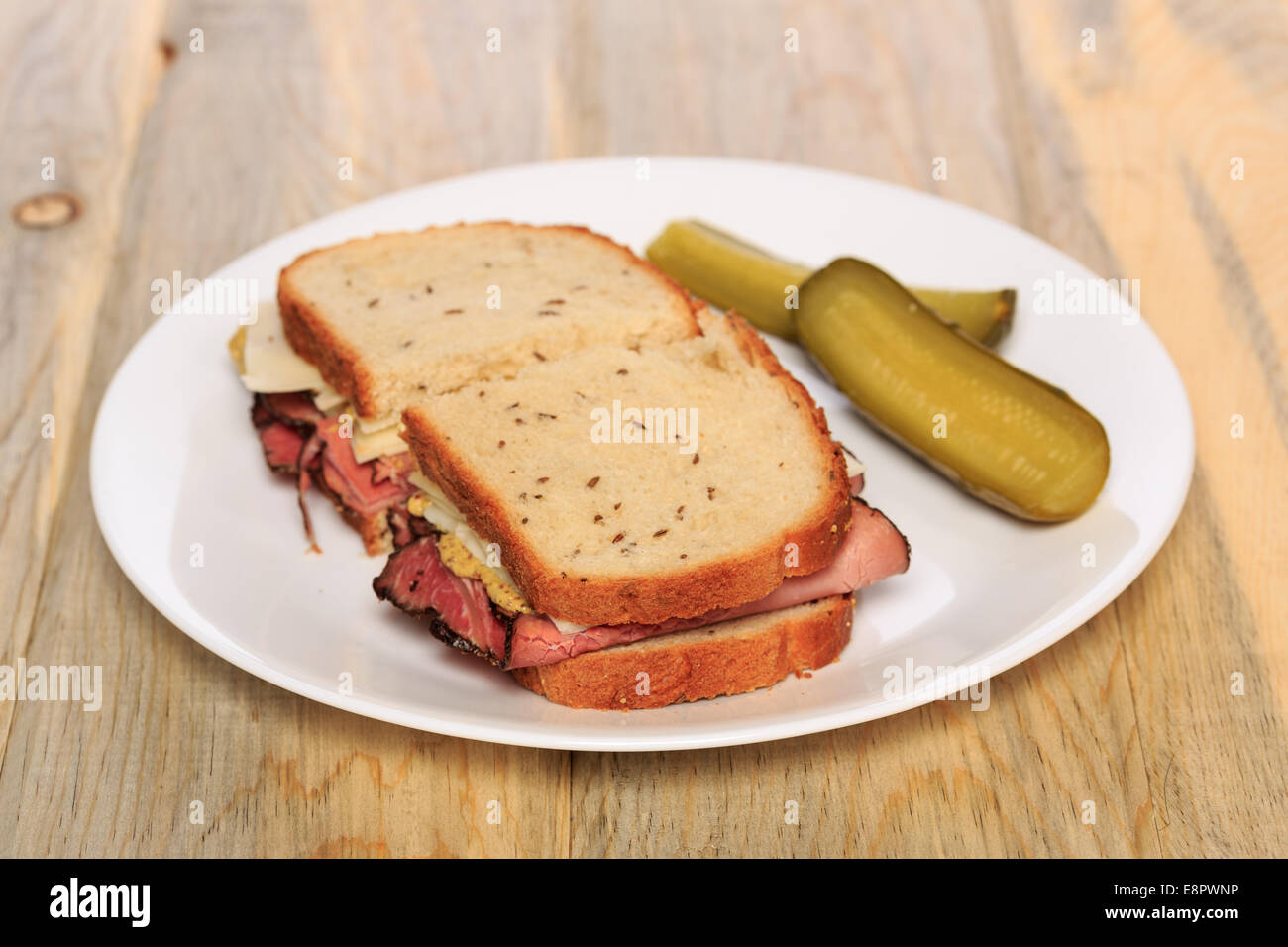 Pastrami sandwich on Jewish Rye bread with swiss cheese, mustard, and kosher dill pickles Stock