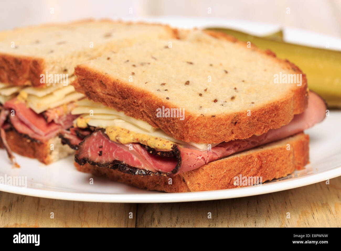 Pastrami sandwich on Jewish Rye bread with swiss cheese, mustard, and kosher dill pickles Stock