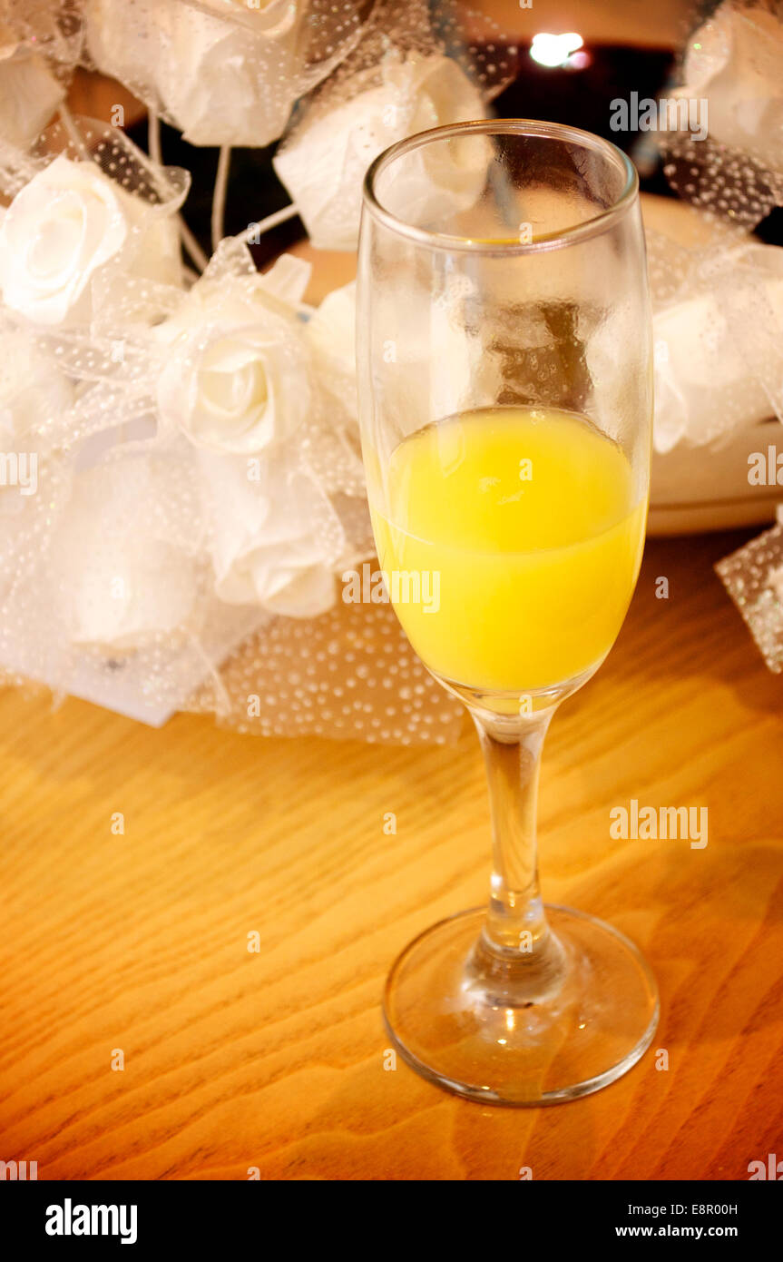 A flute of Buck's Fizz with the Bridal flowers in the background Stock Photo