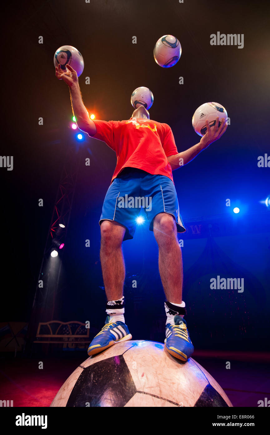 Zhora Oganisyan, the football juggler from The Moscow State Circus, attempts to Balance on a giant football whilst juggling 3 footballs with his hand simultaneously and attempting to ‘keep up’ an extra football by flicking it from foot to foot, at Alexandra Palace  Featuring: Zhora Oganisyan Where: London, United Kingdom When: 10 Apr 2014 Stock Photo
