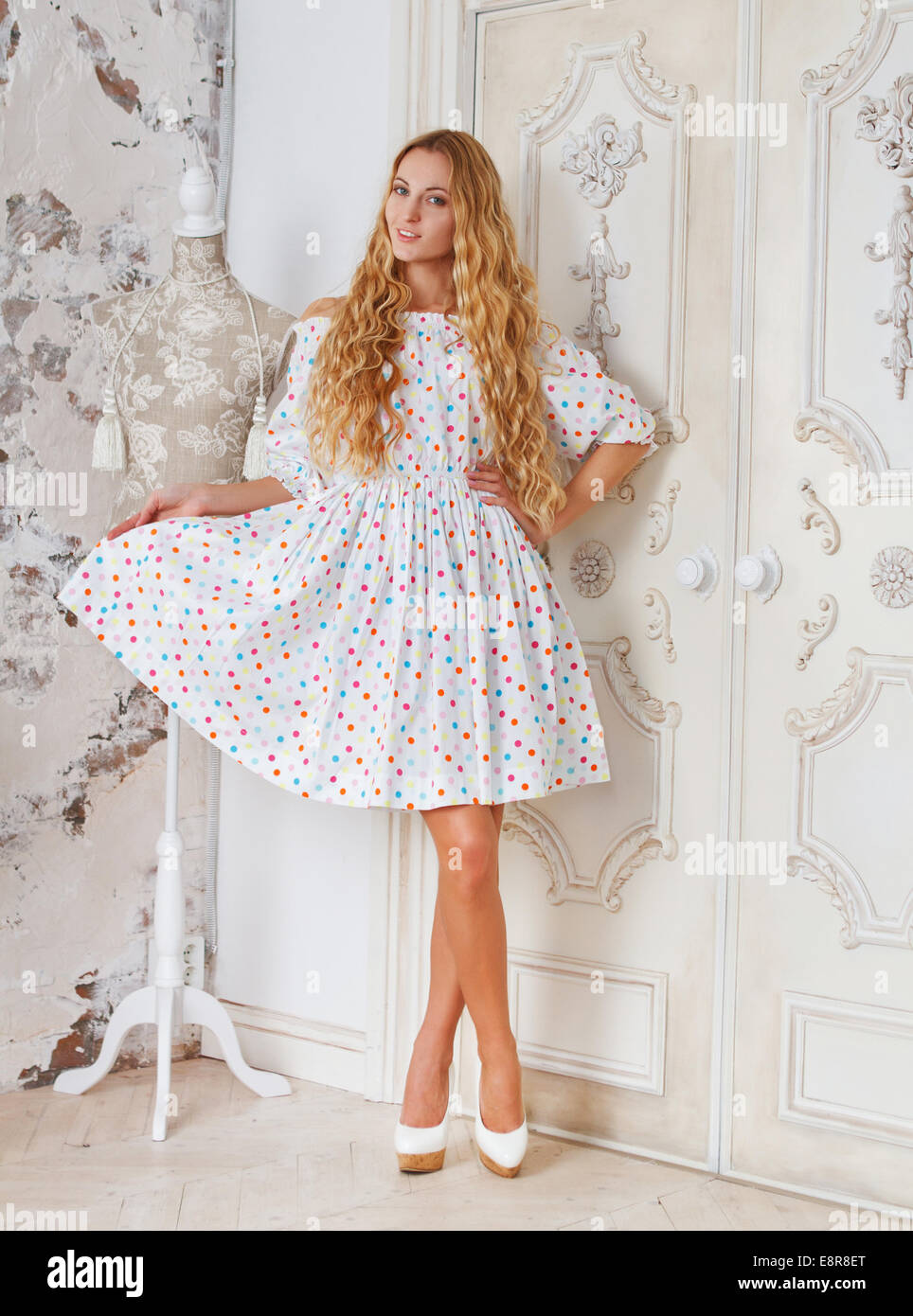 Portrait of the beautiful blond girl in polka dots dress in living room ...