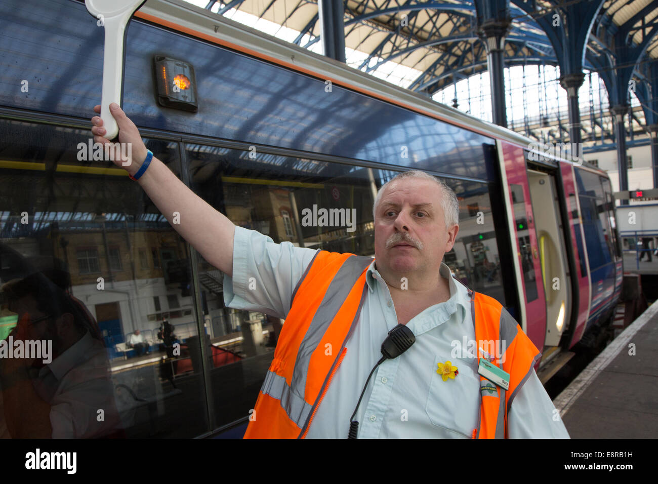 A Signal Man at a railway station prepares to blow his whistle to