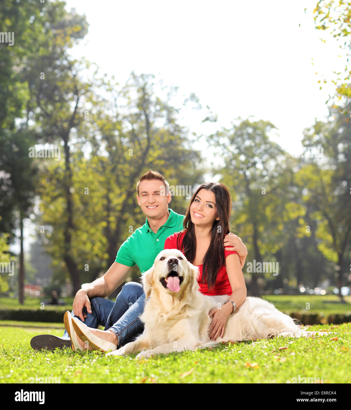Young couple sitting in park with a dog shot with tilt and shift lens ...