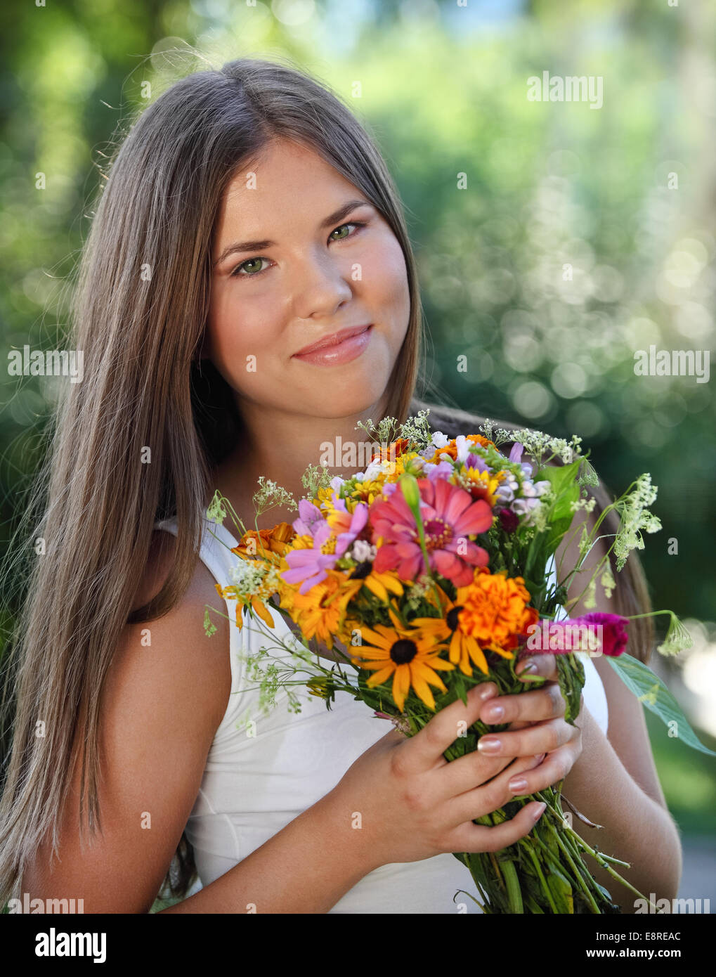 Beautiful young girl with flowers in summer park Stock Photo - Alamy