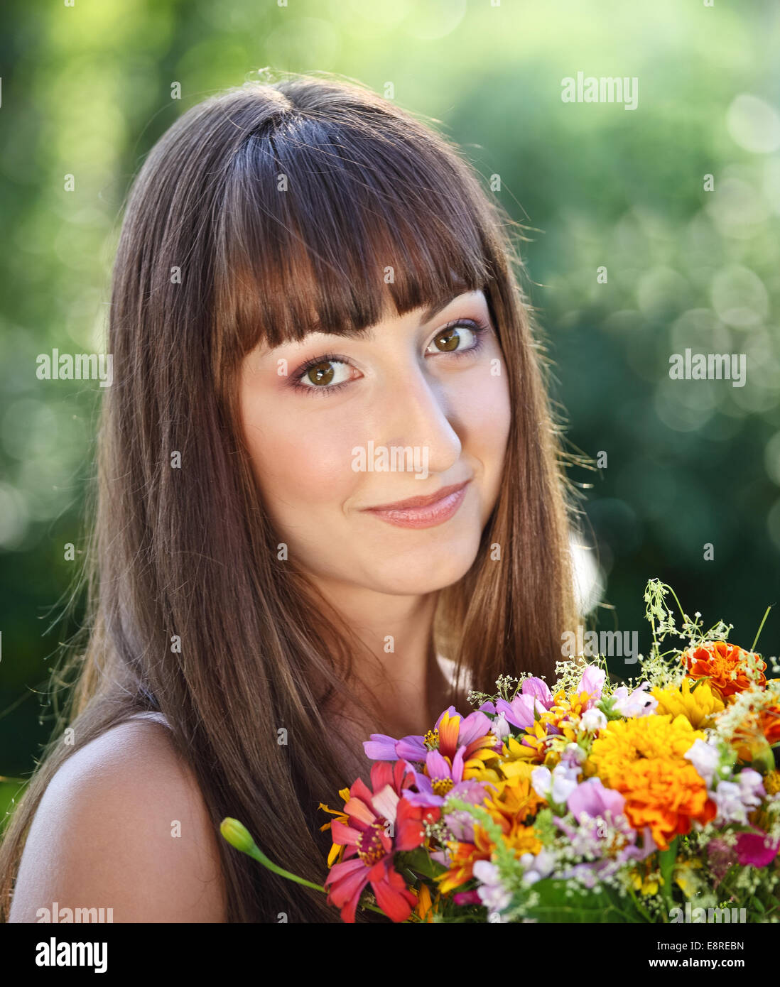 Beautiful young girl with flowers in summer park Stock Photo - Alamy
