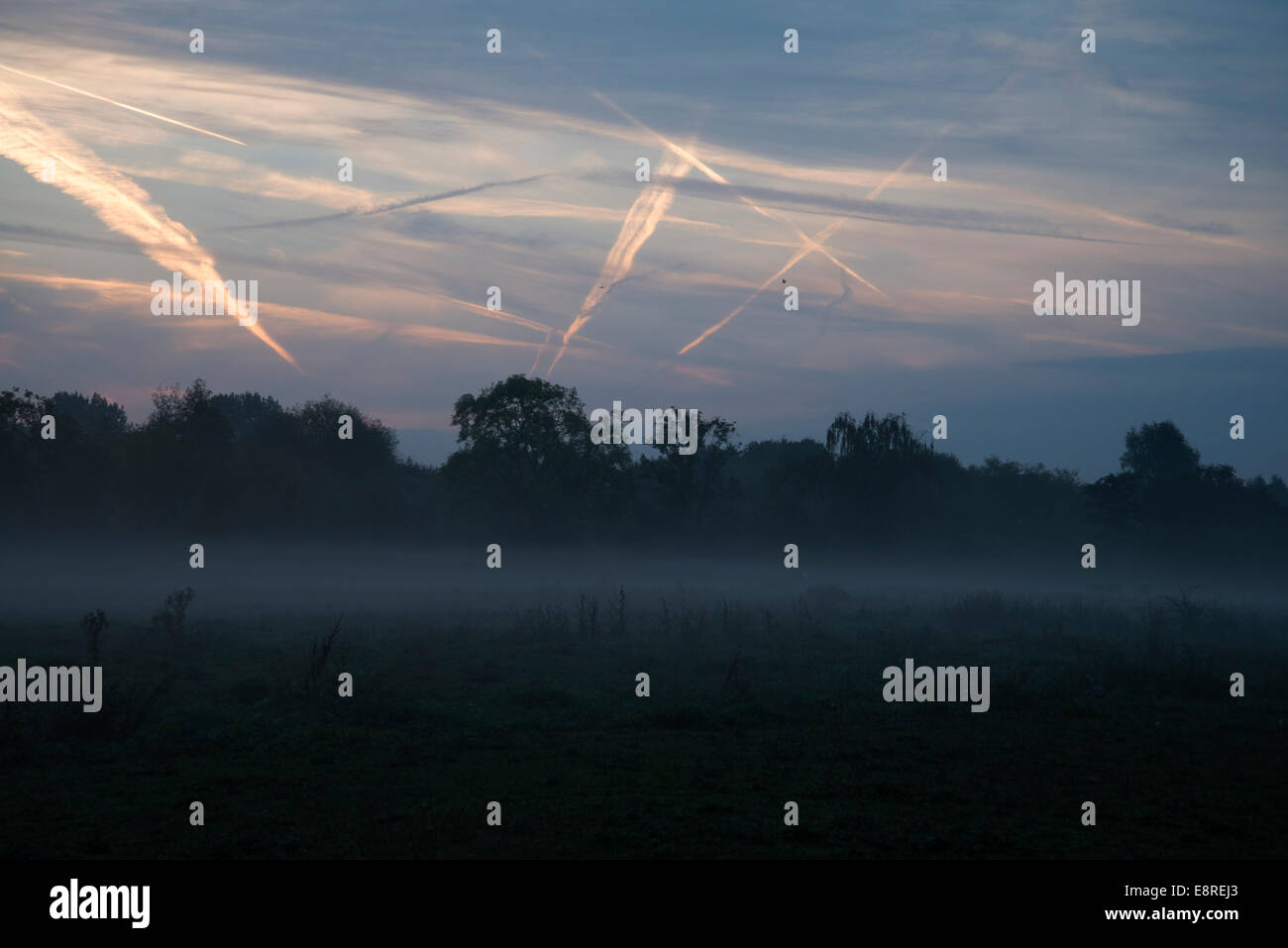 October 2014: Early morning misty landscape with aircraft contrails in blue sky. In Oxford, England Stock Photo