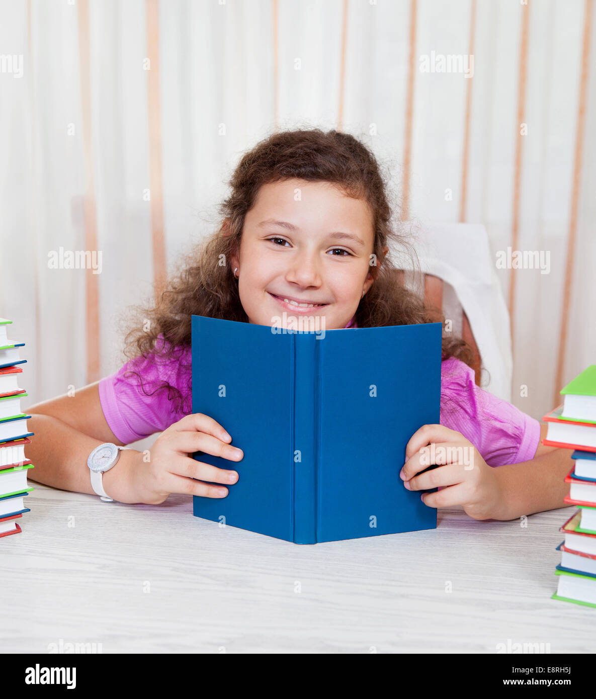 Little brunette smiling girl with piles of books Stock Photo - Alamy