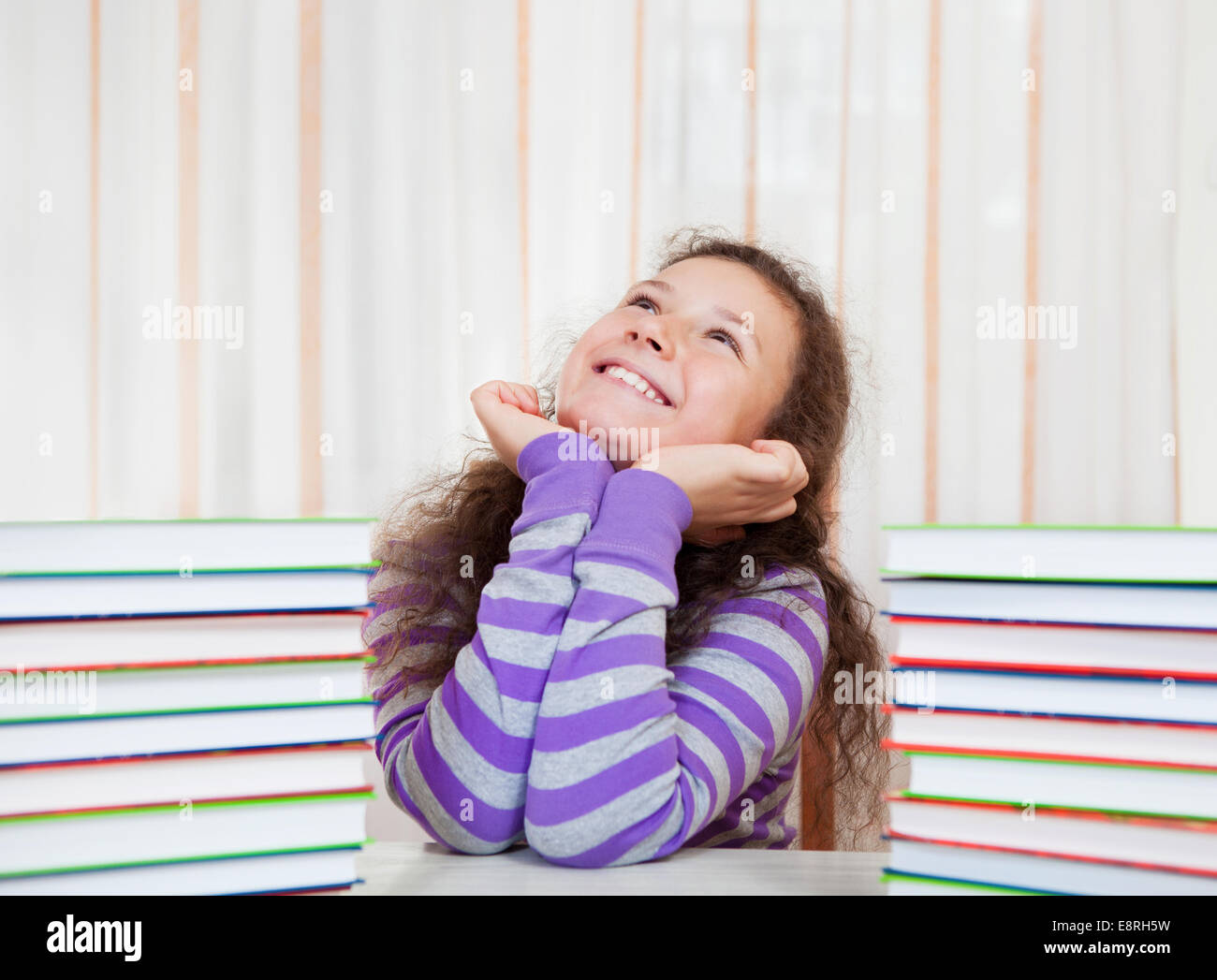 Little brunette smiling girl with piles of books Stock Photo - Alamy