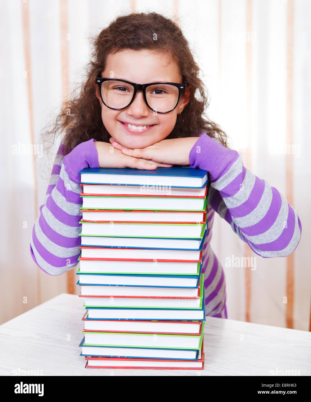 Little brunette smiling girl with pile of books Stock Photo - Alamy
