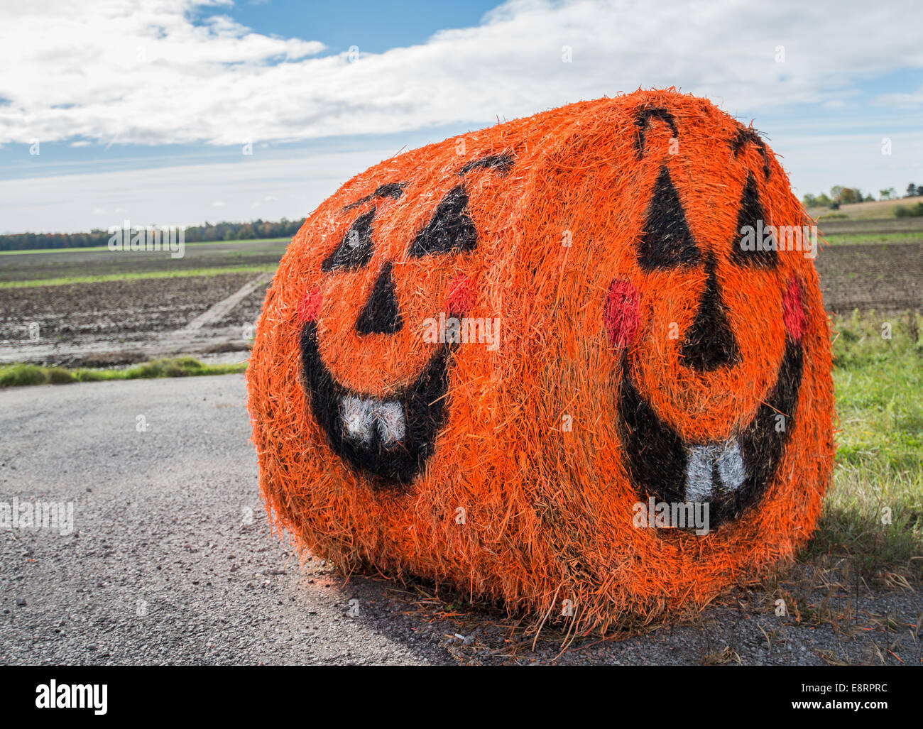 A straw bale painted to look like a smiling Jack O Lantern. Stock Photo