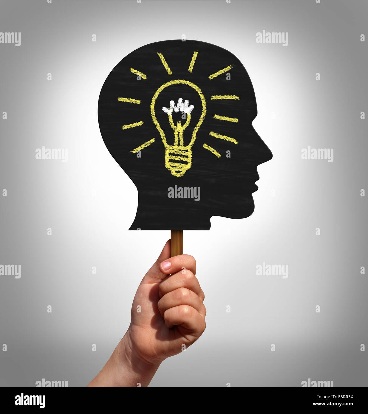 Education advocacy concept and the rights for children to get access to affordable school training and  learning as a hand holding up a placard sign shaped as a head with a drawing of a light bulb as a metaphor for social youth support. Stock Photo
