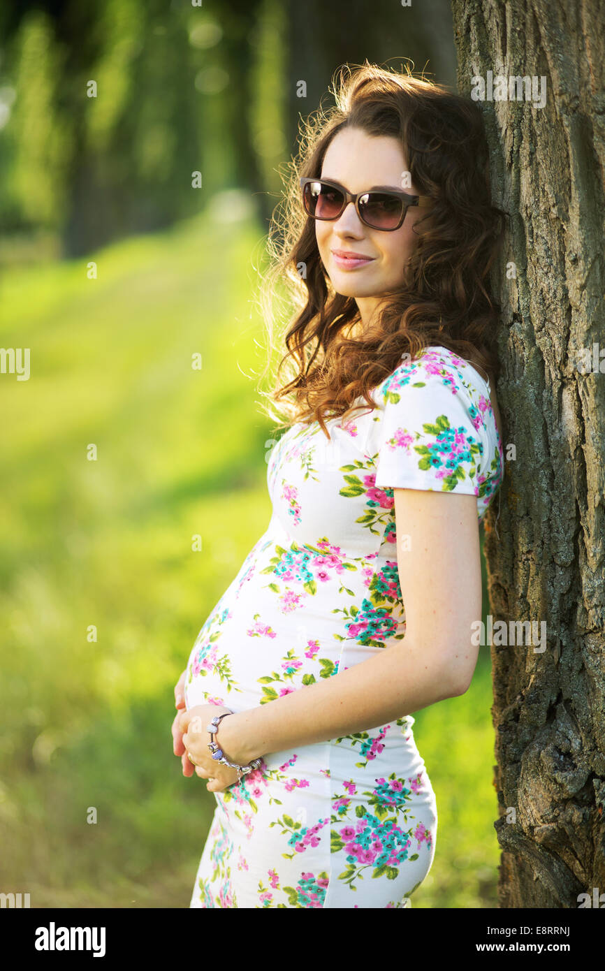 Marvelous pregnant mom leaning against the tree Stock Photo
