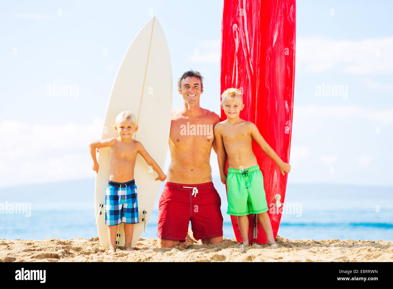 Father and Two Young Sons Going Surfing at the Beach Stock Photo