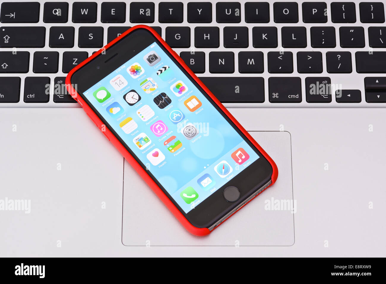iPhone 6 in red case on an Apple Macbook keyboard Stock Photo