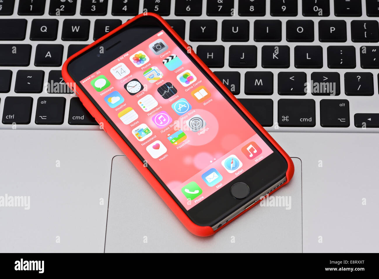 iPhone 6 in red case on an Apple Macbook keyboard Stock Photo