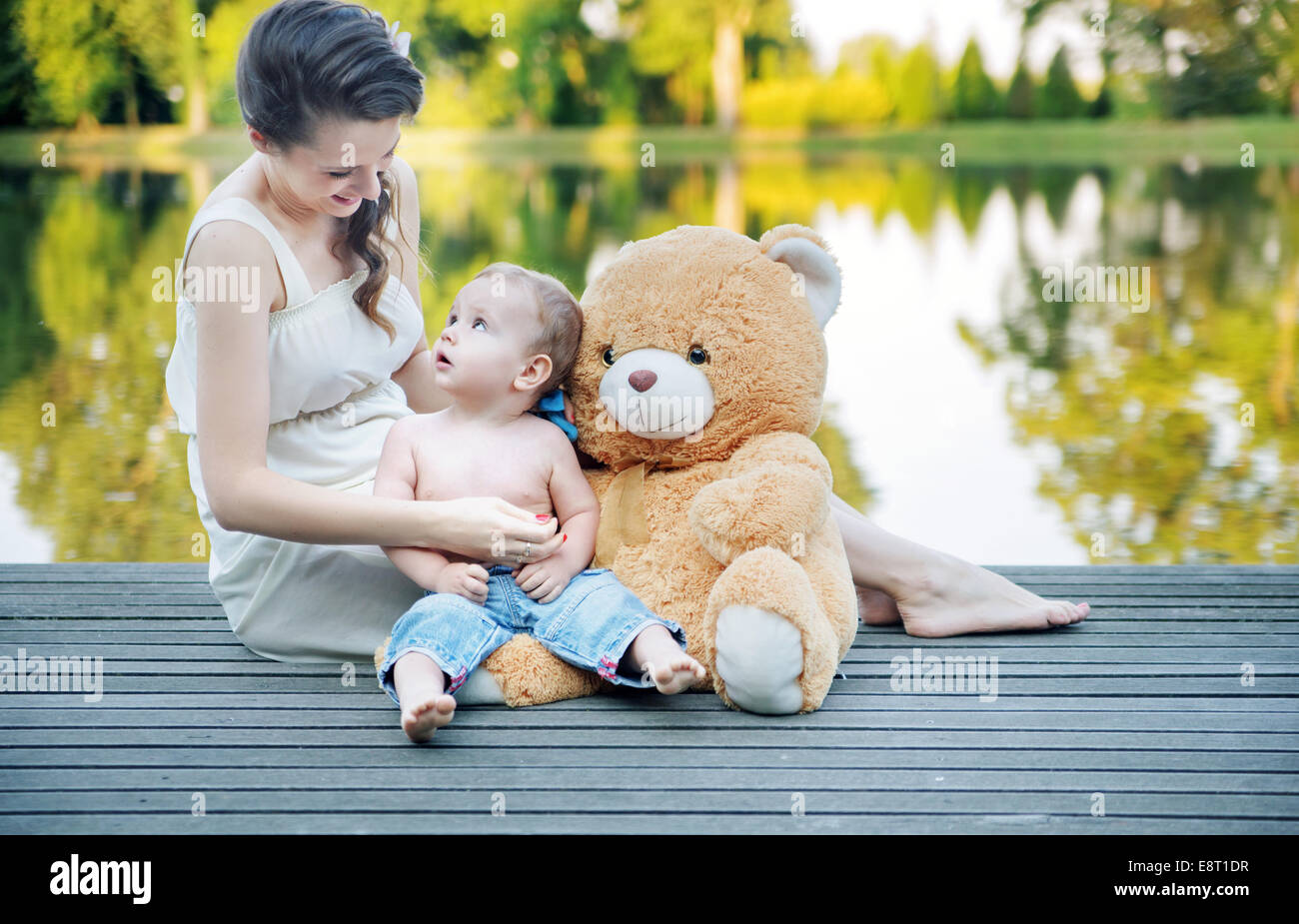 Mom looking at her baby playing teddy bear Stock Photo - Alamy
