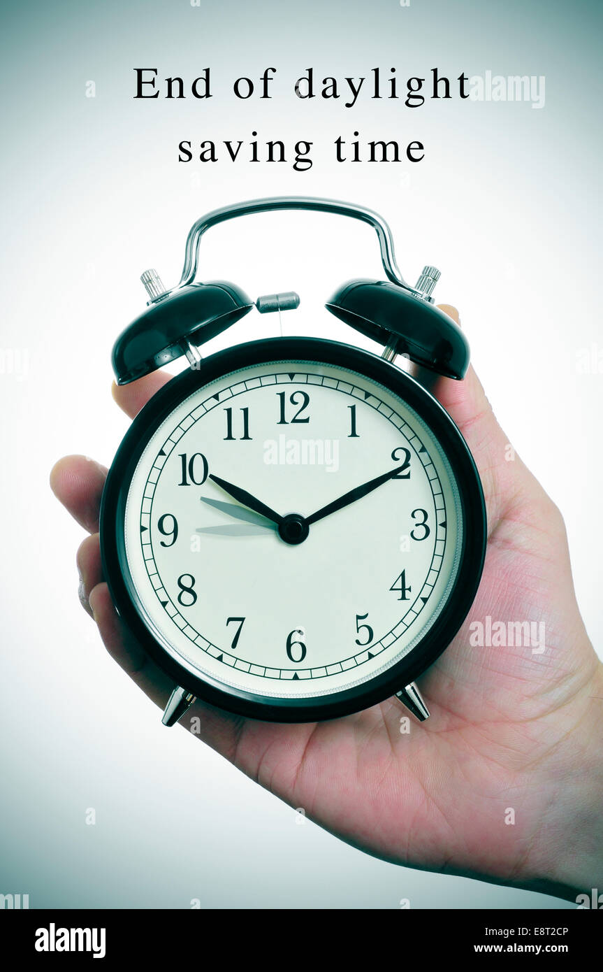 an alarm clock adjusting backward one hour and the text end of daylight saving time Stock Photo