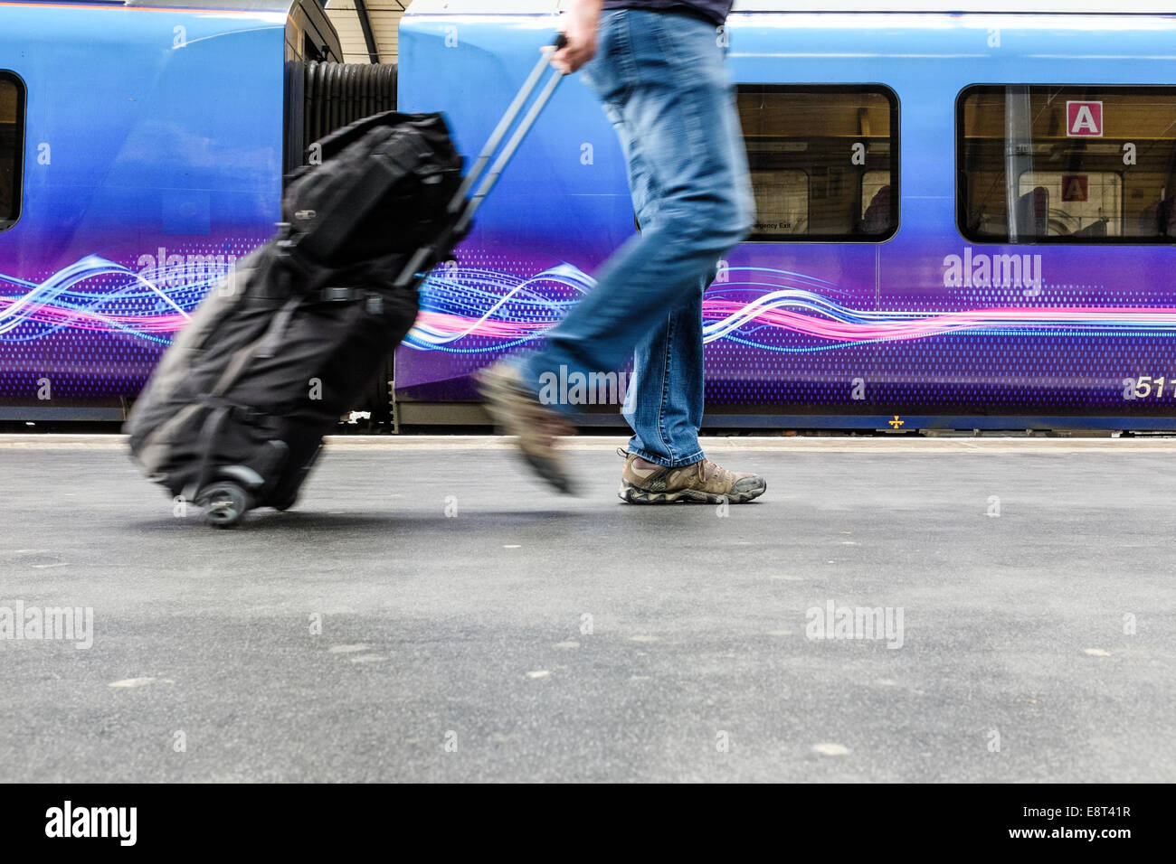 A male train passenger pulls his luggage either leaving the train or getting on it. Travel concept conceptual transport Stock Photo