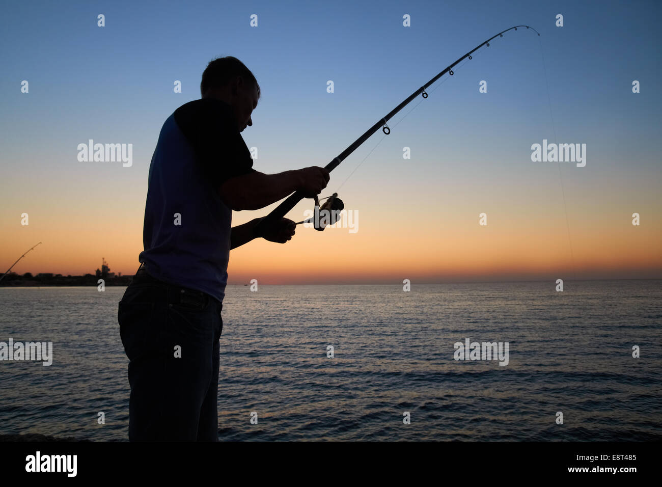 Fisherman fishes on the lake. Silhouette at sunset Stock Photo - Alamy