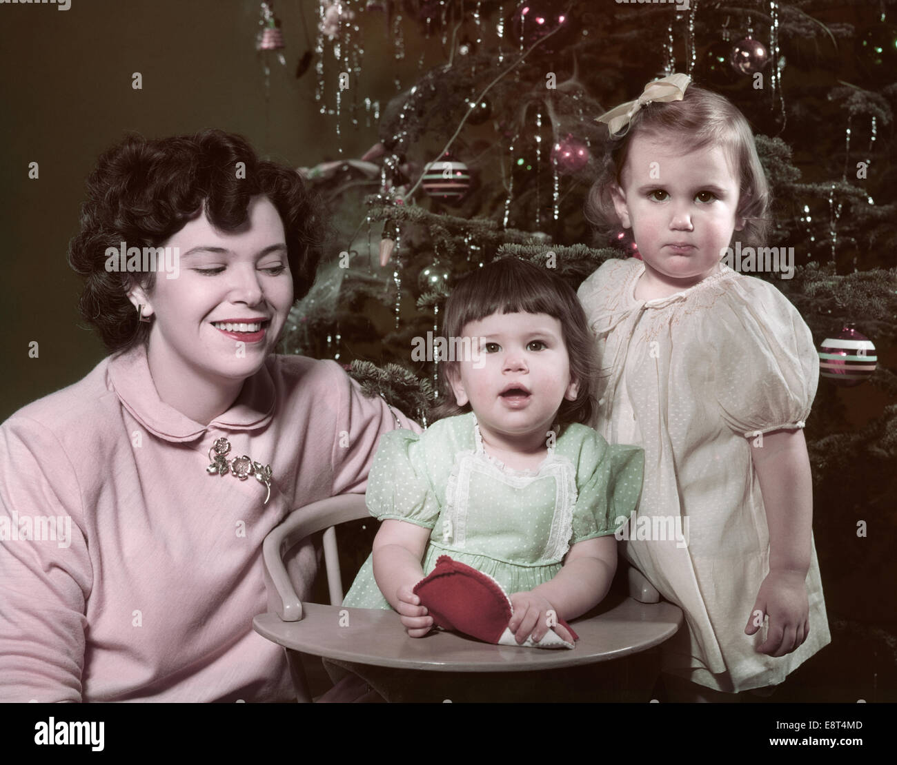 1950s PORTRAIT SMILING MOTHER TWO CHILDREN GIRLS BY CHRISTMAS TREE Stock Photo