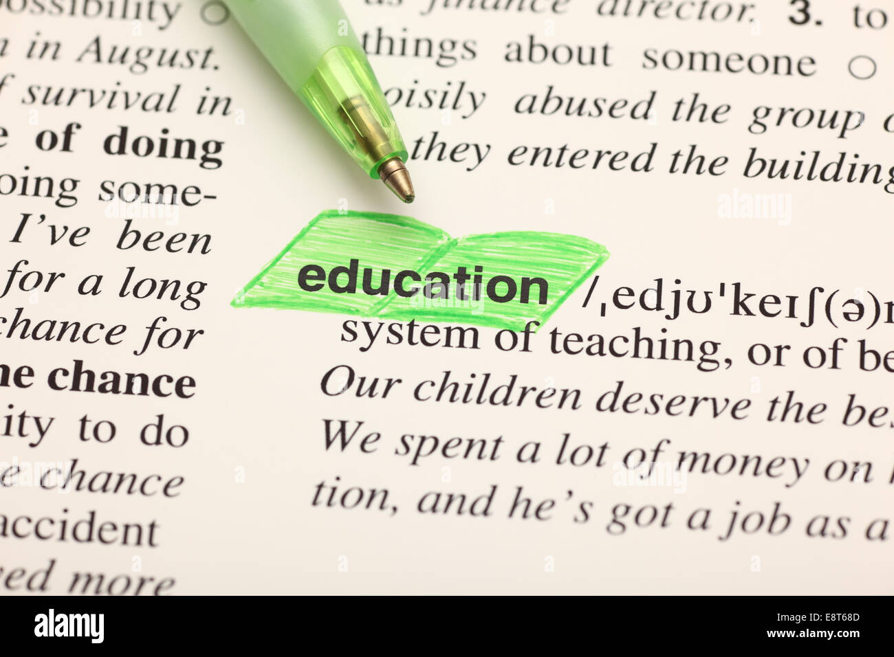 The word "education" highlighted in green on a dictionary and ballpoint