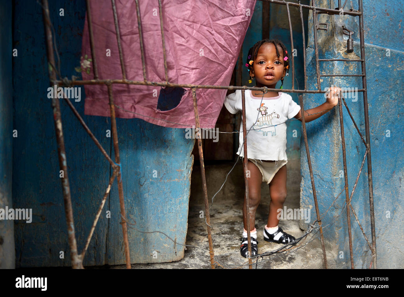 Girl behind a fence in a doorway, Fort National slum, Port-au-Prince, Haiti Stock Photo