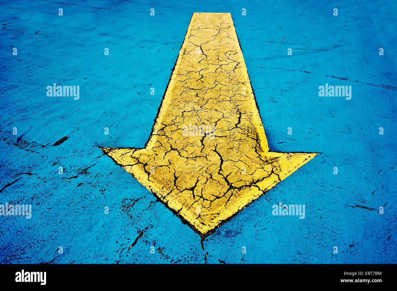 Yellow arrow on blue concrete with cracks Stock Photo