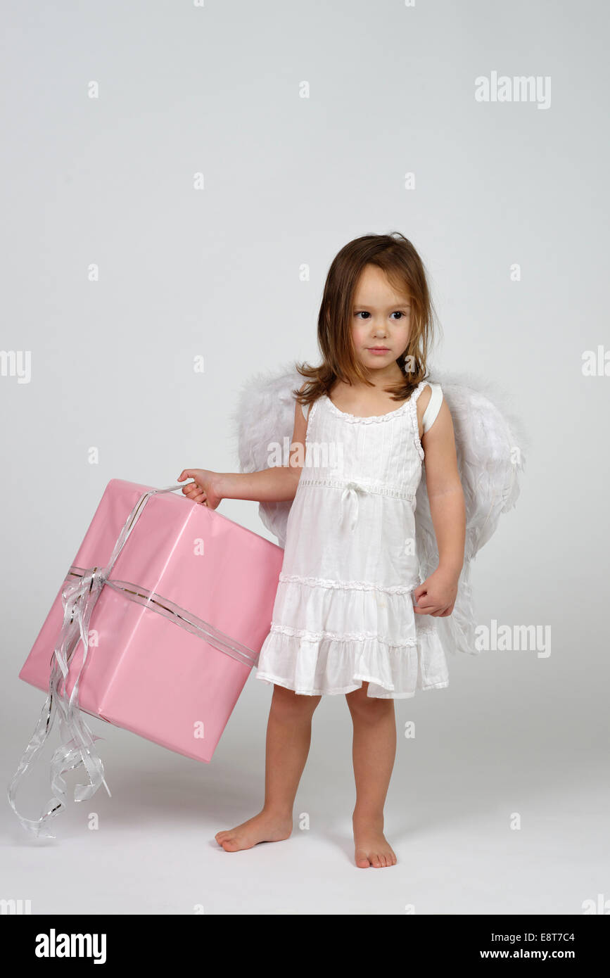 Girl dressed as angel, with Christmas gift Stock Photo