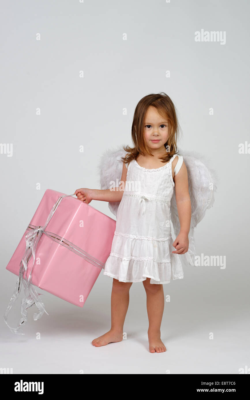 Girl dressed as angel, with Christmas gift Stock Photo