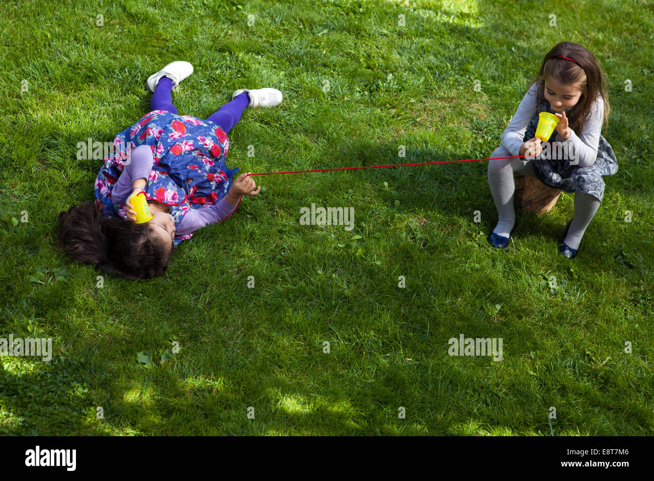 Two girls playing in park with toy phone Stock Photo