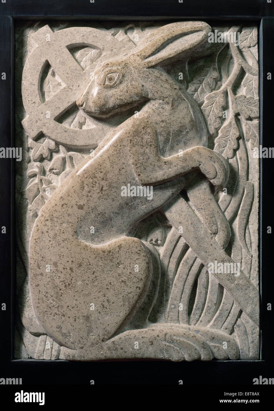 Modern stone carving of hare with Celtic cross & oak leaves at St Melangell's church, Powys, Mid Wales: legend of Melangell protecting a hunted hare. Stock Photo