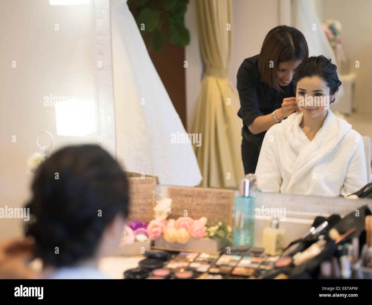 Mixed race, Asian / American bride has makeup and hair styled by stylist before wedding Stock Photo