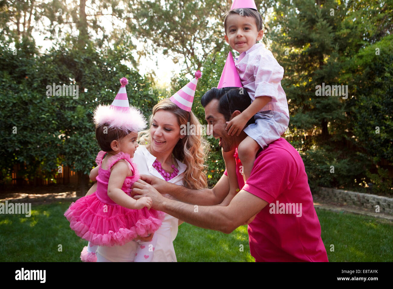 Family wearing party hats together in backyard Stock Photo