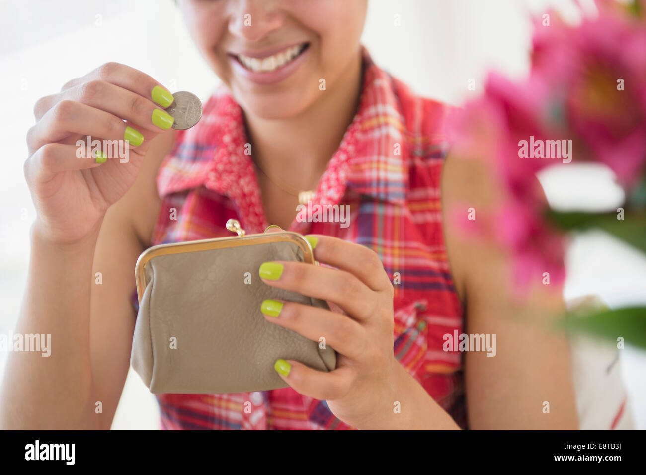 Mixed race woman putting coin into purse Stock Photo