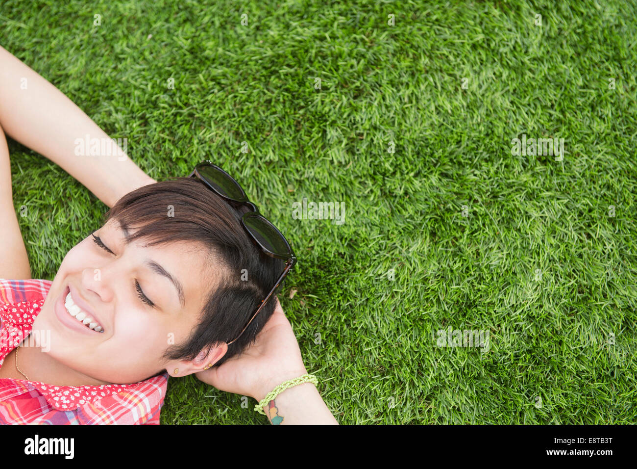 Mixed race woman laying in grass outdoors Stock Photo