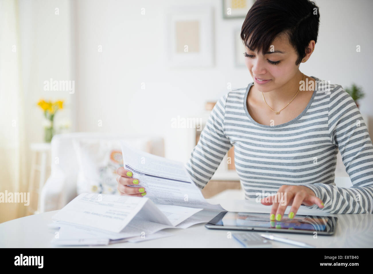 Mixed race woman paying bills on digital tablet Stock Photo